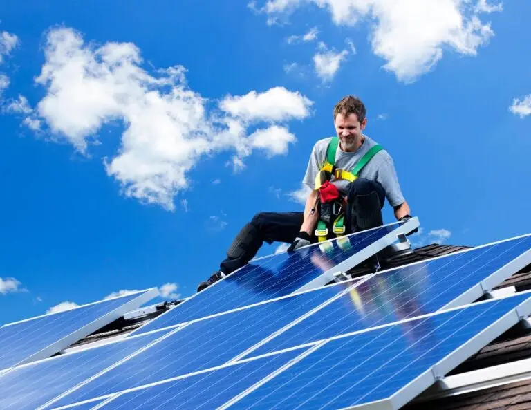 solar technician installing rooftop solar panel on sunny day.